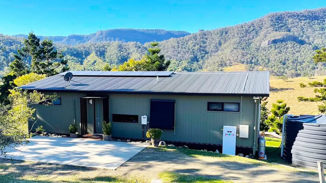Home with rooftop solar panels and a battery on the outside wall