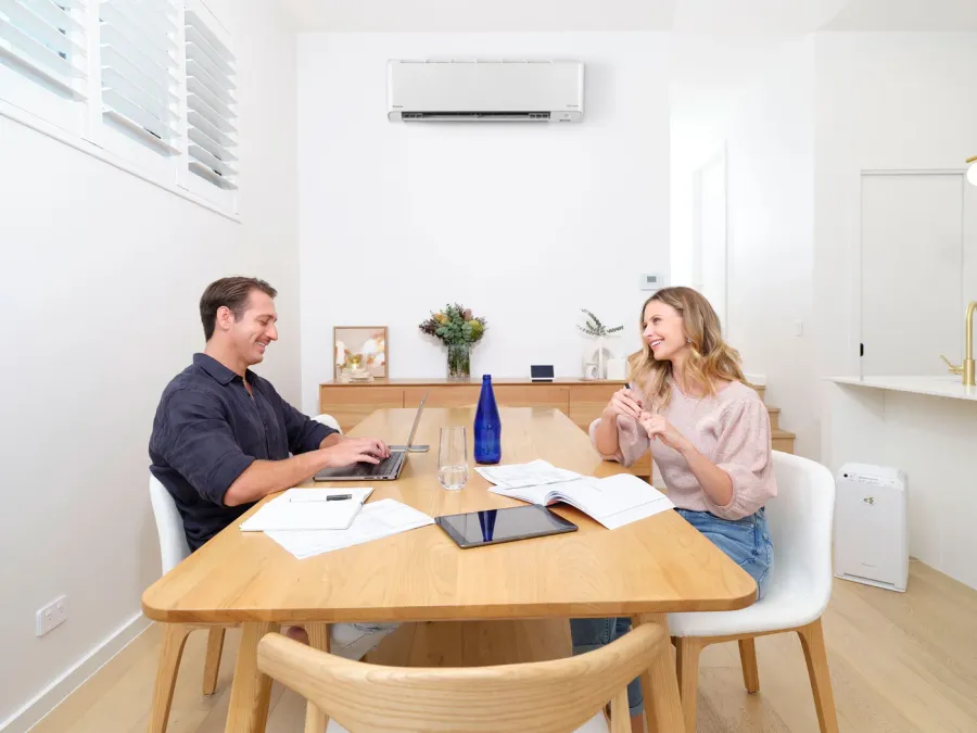 A couple at their dining table under a wall-mounted reverse-cycle air conditioner